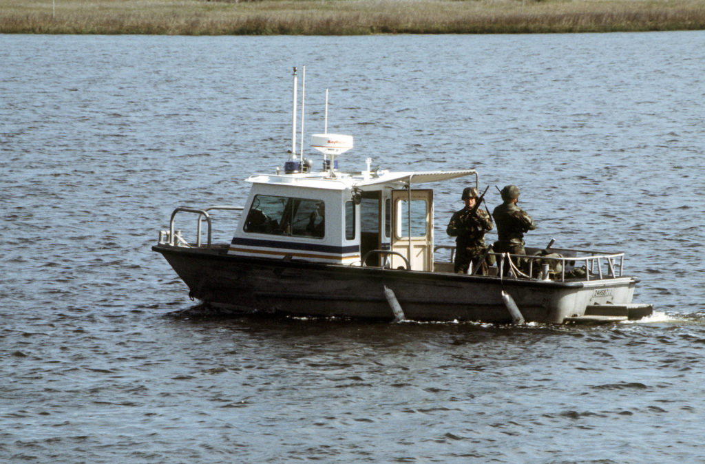 The 1990s. Marines of the Security Force Company stand guard with M-16A2 assault rifles while patrolling in a boat near the special weapons area of the submarine base.